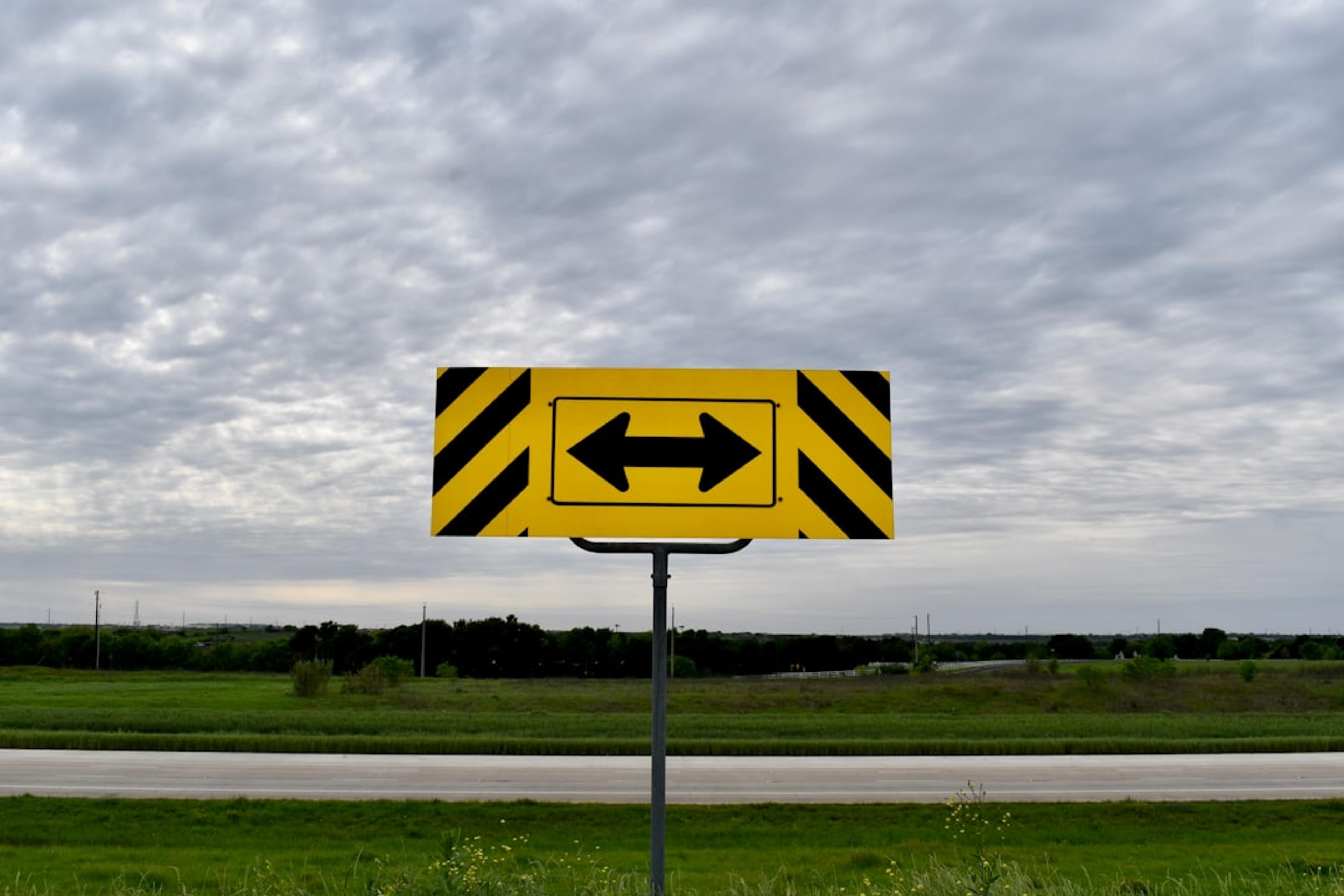 a yellow and black arrow sign on a pole
