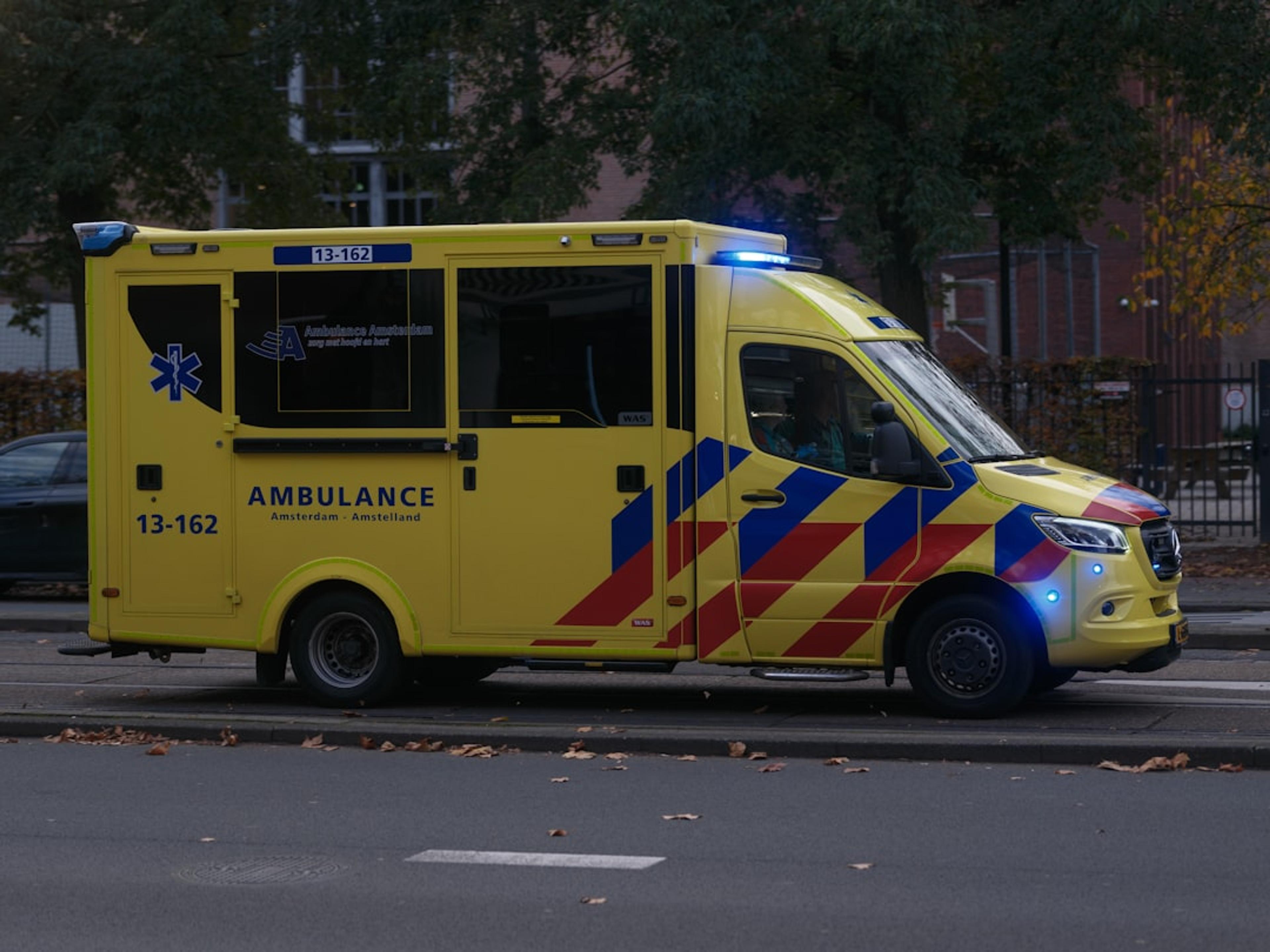 A yellow ambulance with blue lights on.