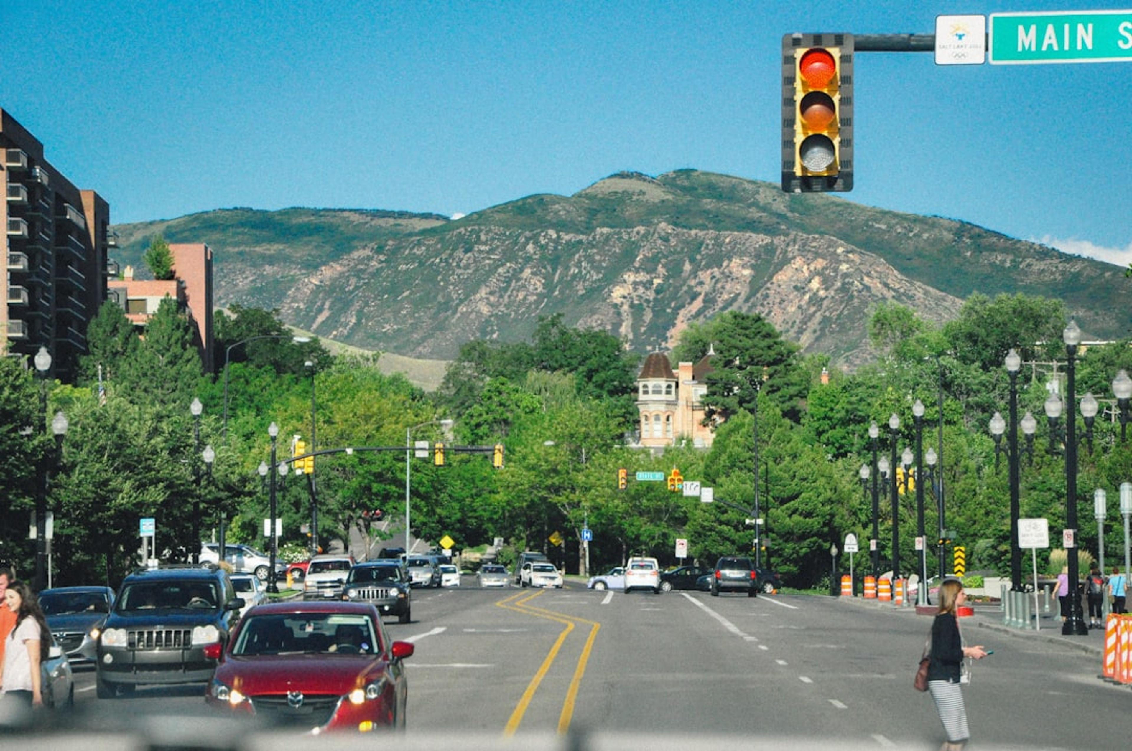 Cars drive on a city street with a mountain view.