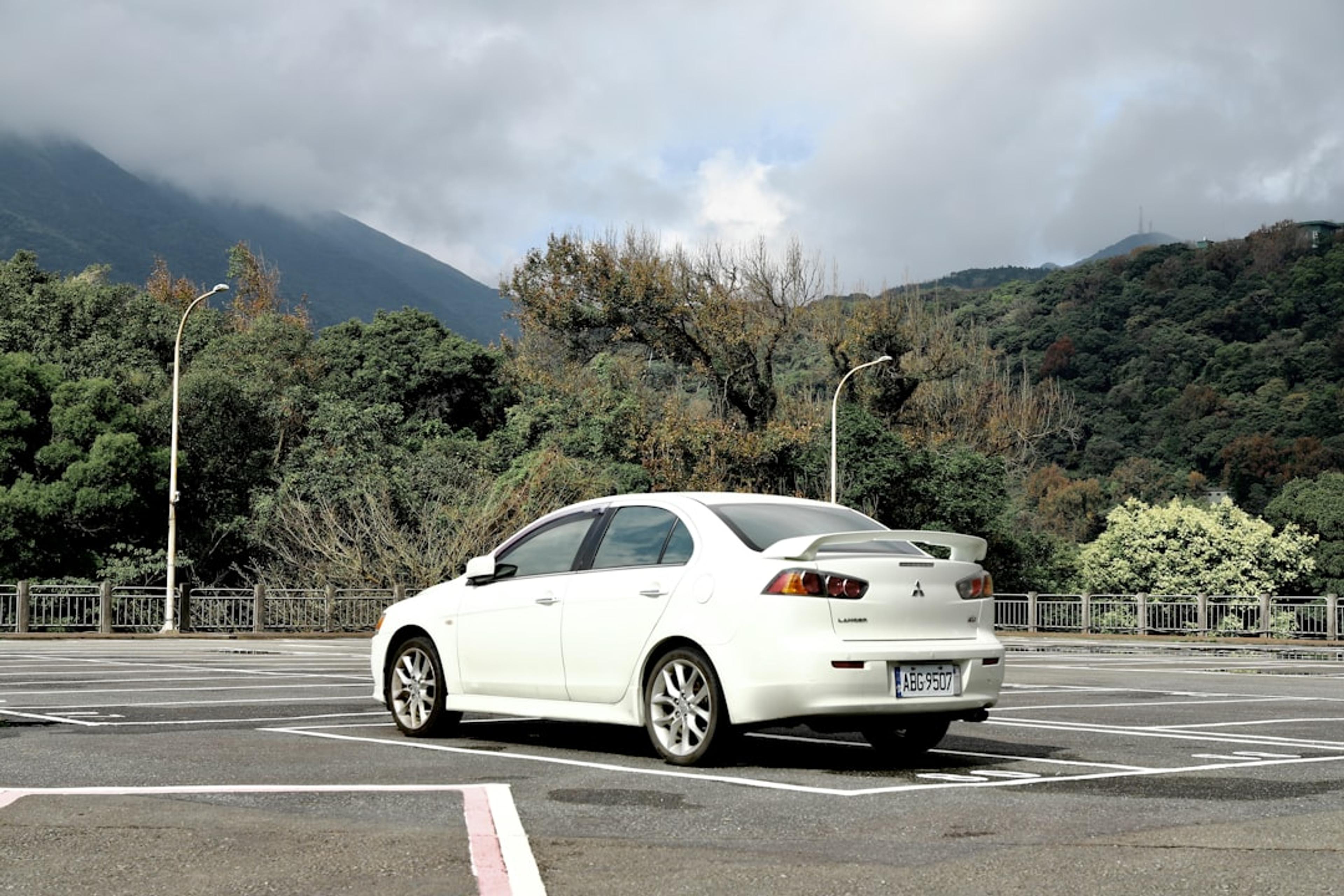 white sedan on road near green trees during daytime