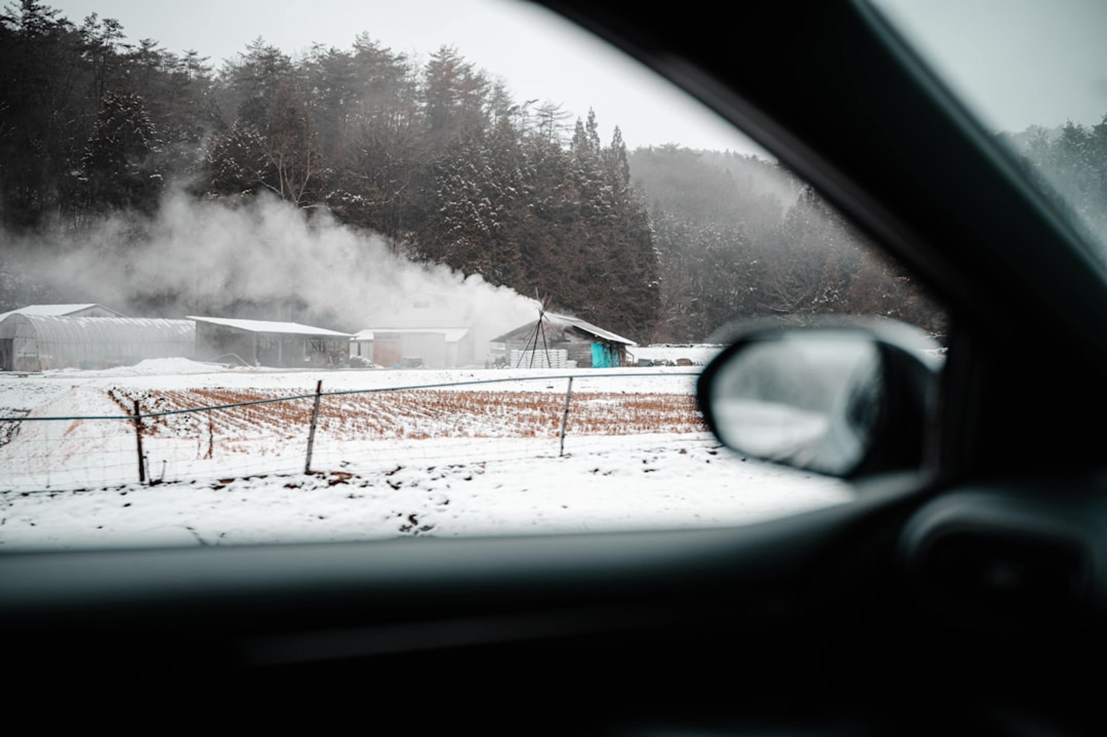 a view of a snow covered field from a car window
