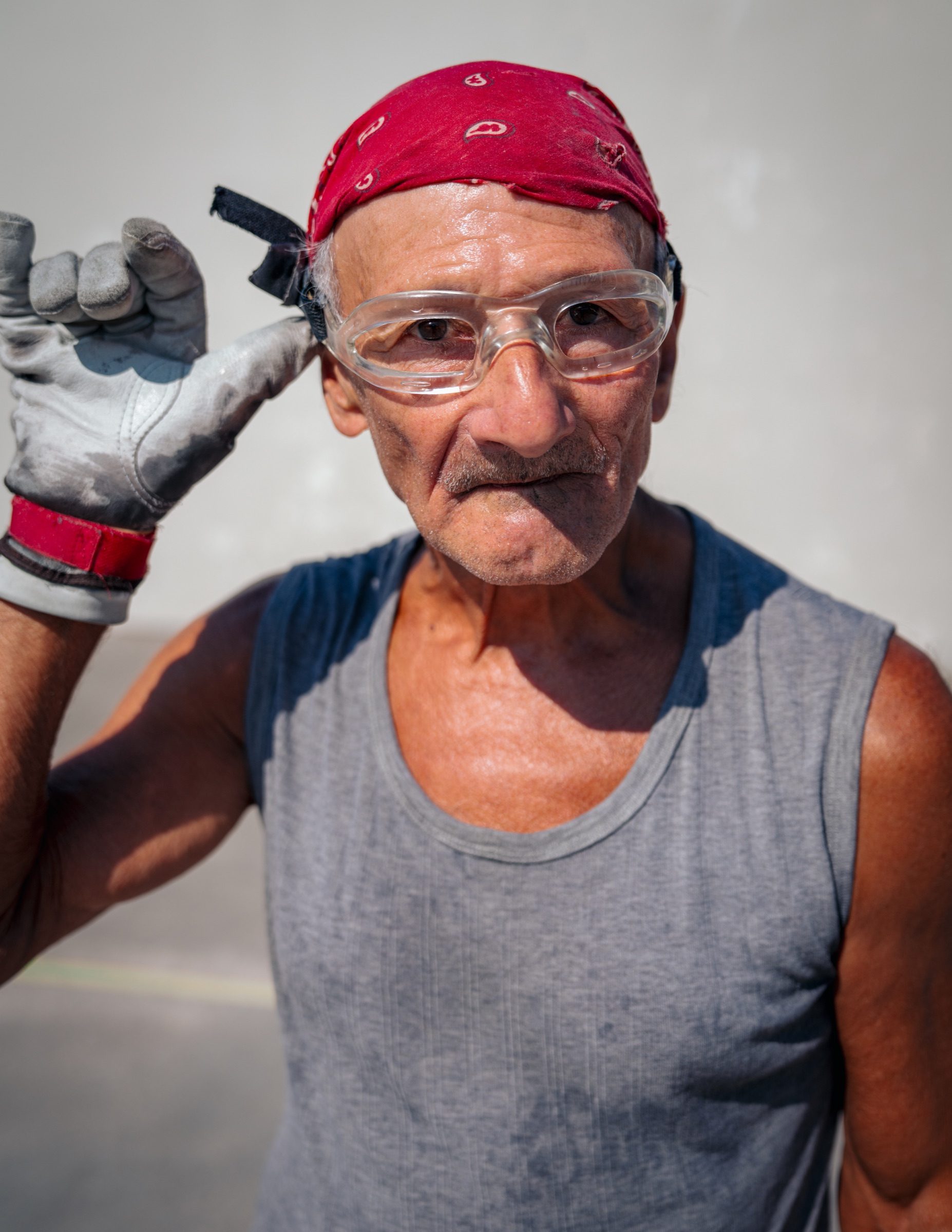 Portrait of a worker in safety glasses, a red bandana, and work gloves.