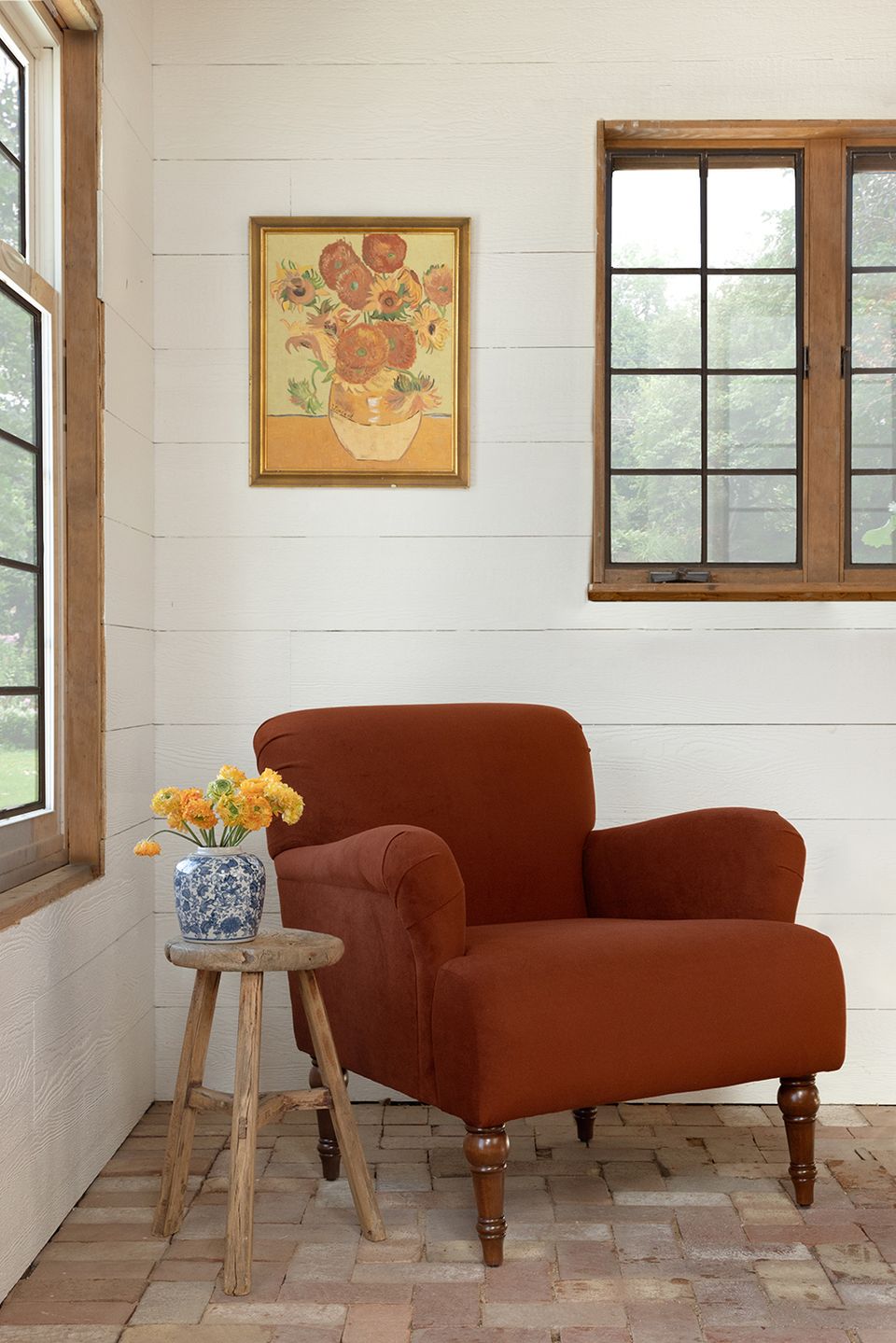 Farmhouse-inspired space with rust-red rolled-arm chair against white shiplap walls and warm wood accents.