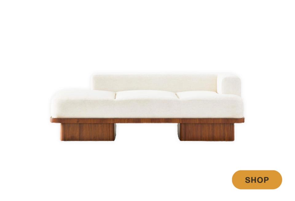 Mid-century daybed with cream cushion, sculptural wood base, and warm walnut tone.