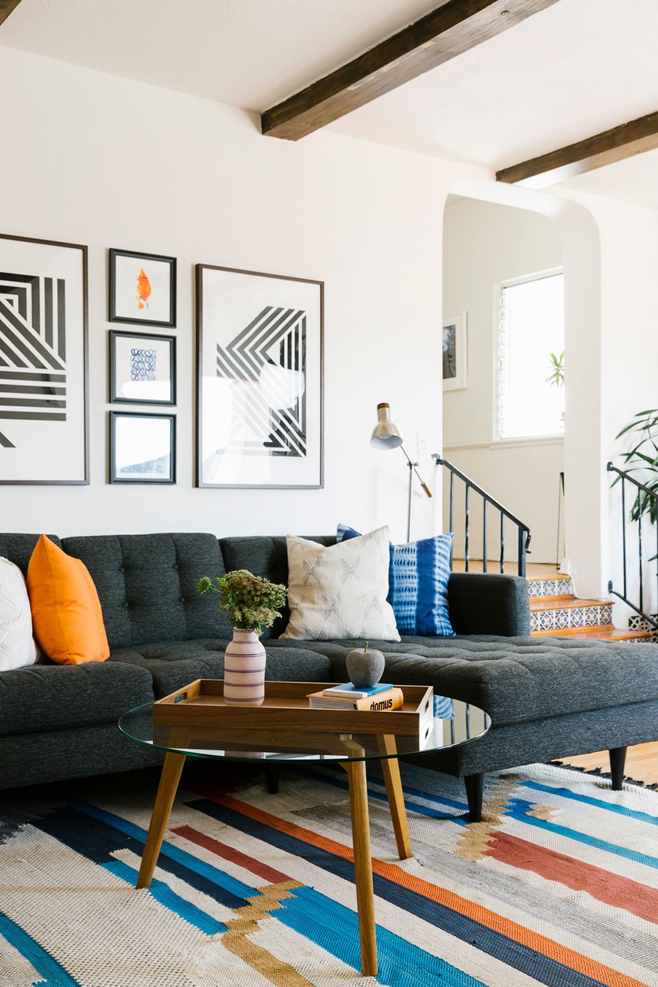 Mid-century modern living room with colorful striped rug, dark sofa, and graphic wall art