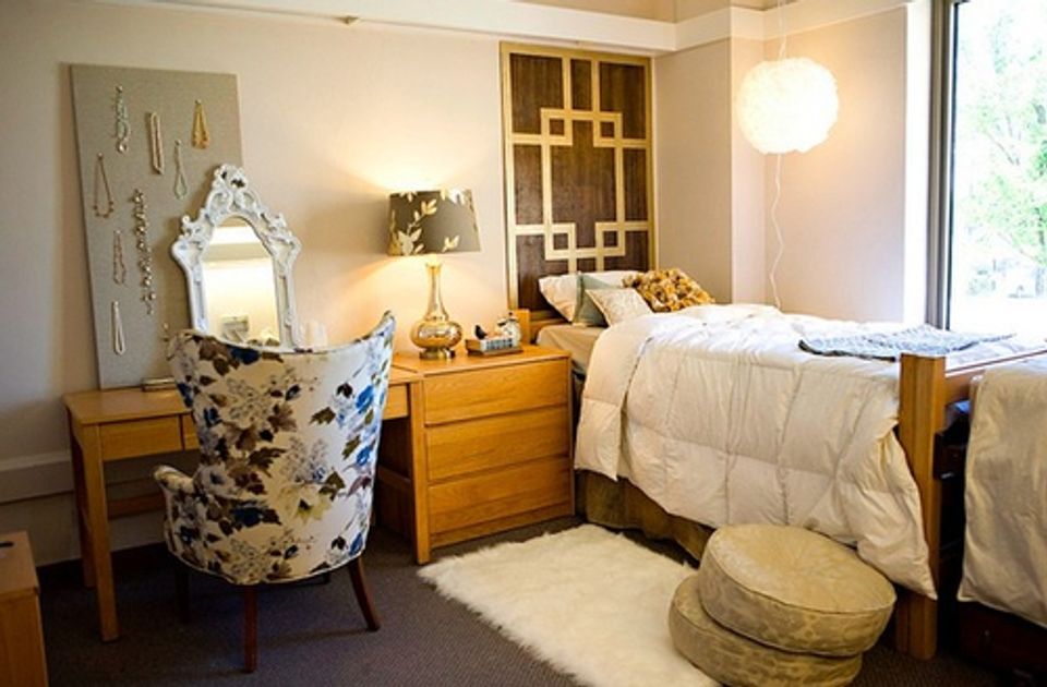 Mid-century inspired dorm blending warm wood furniture, cream bedding, geometric wall art, and soft lighting