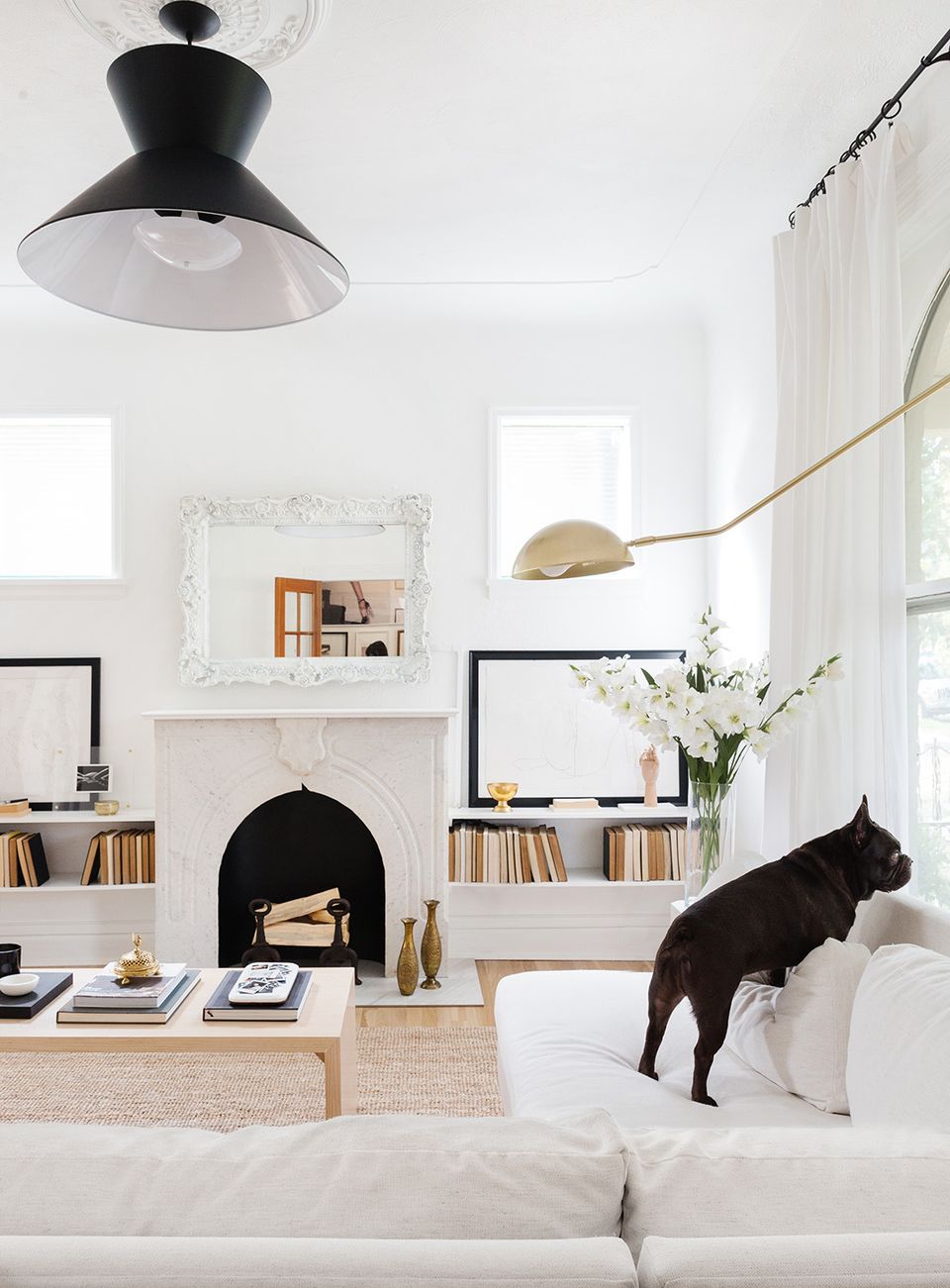 Scandinavian living room with black pendant light, fireplace shelving, and airy white design