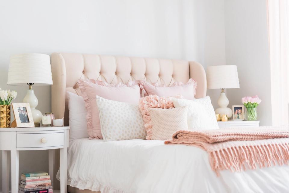Soft feminine bedroom with blush upholstered headboard, pink and white bedding, and layered textures
