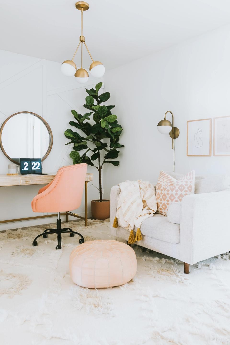 Modern office blending peach chair, brass lighting, lush green plant, and soft sculptural elements