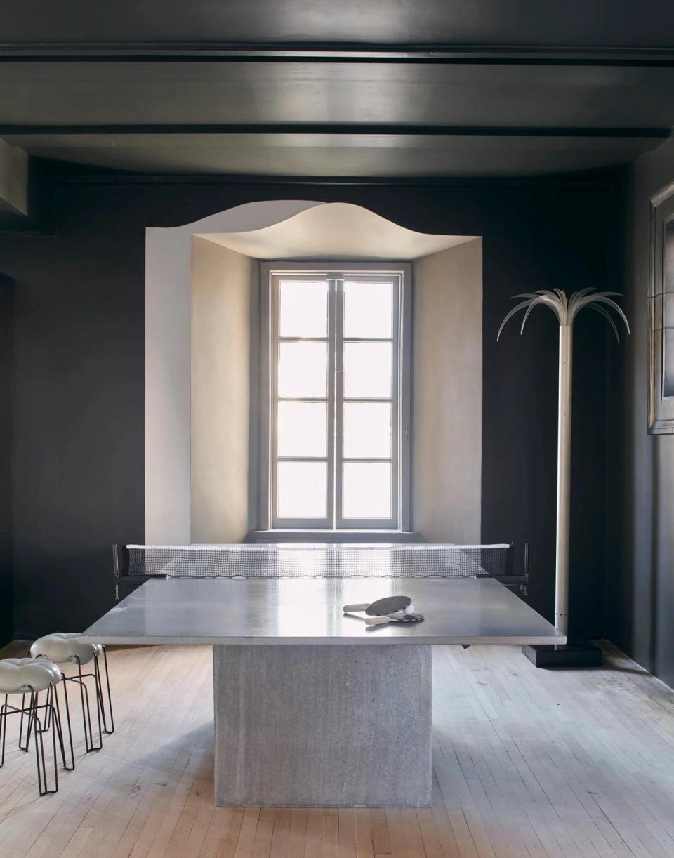Minimalist workspace with charcoal walls, concrete island table, natural light alcove, and high-contrast grayscale palette creating calm, focused atmosphere