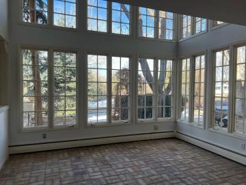 Bright transitional sunroom with extensive grid-patterned glass doors and soft taupe flooring