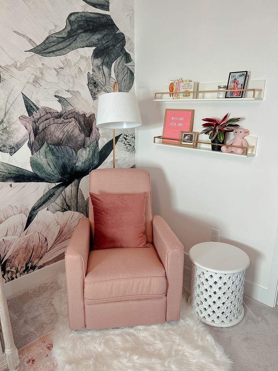 Cozy reading nook with botanical wall mural, dusty pink chair, floating shelves, soft textures