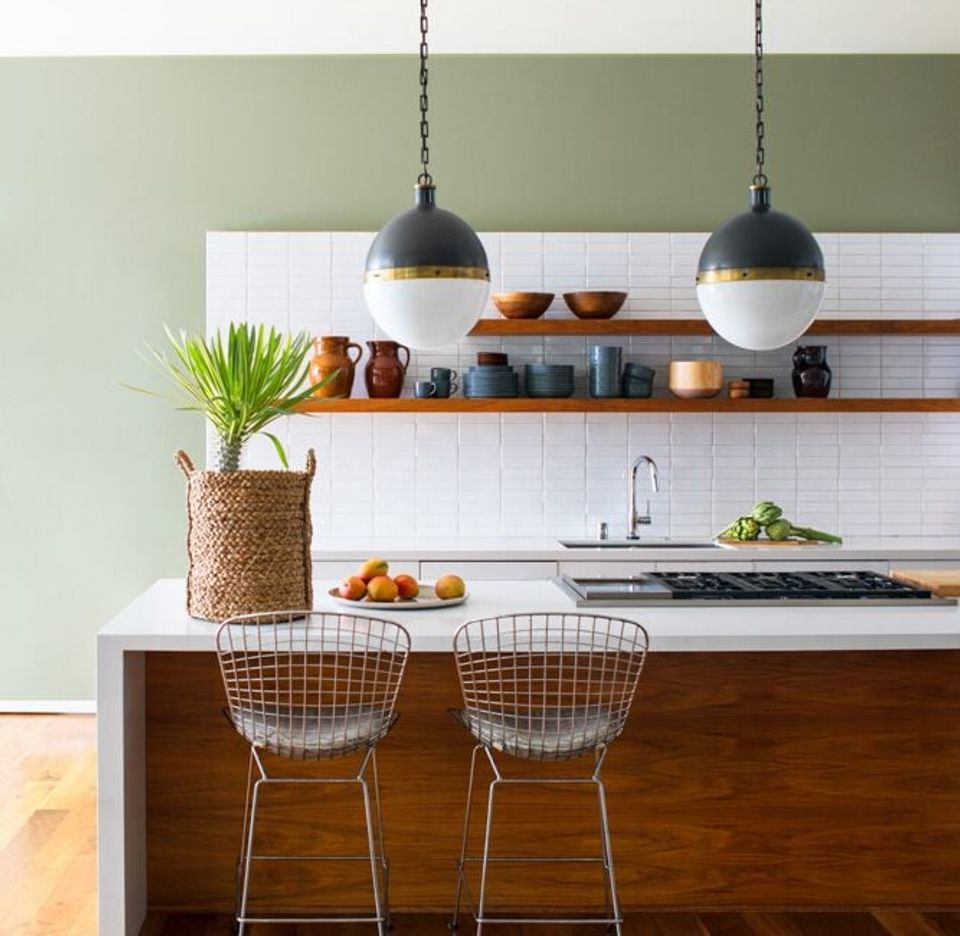 Modern kitchen with sage green upper walls, white subway tiles, and warm wood accents