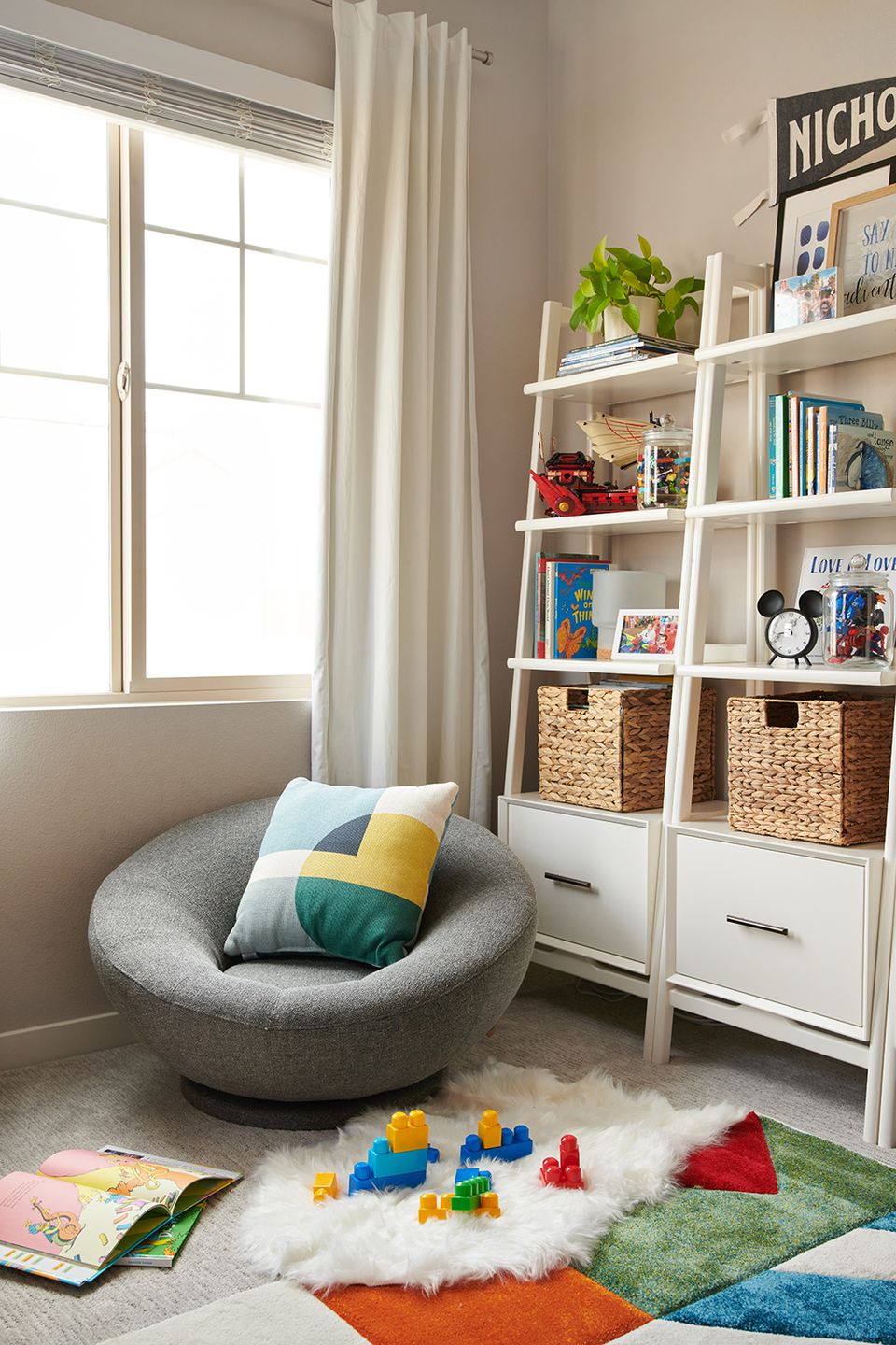 Minimalist Scandinavian reading alcove with gray pod chair, white shelves, and cheerful color blocking