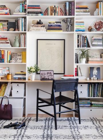 Eclectic maximalist bookshelf with white built-ins, rainbow book collection, art prints, and natural styling accents