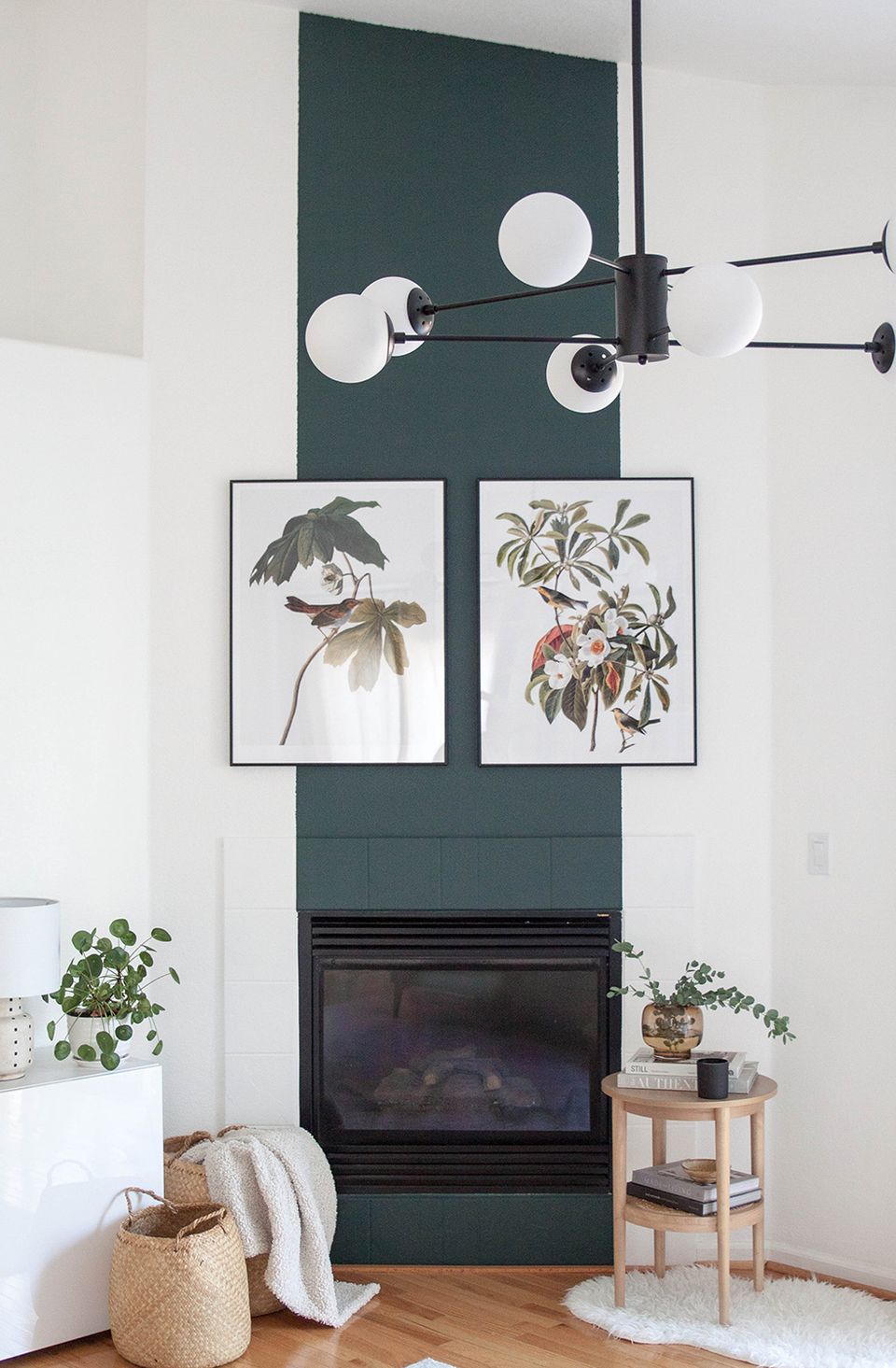 Modern fireplace feature with forest green accent wall, botanical prints, and minimalist styling