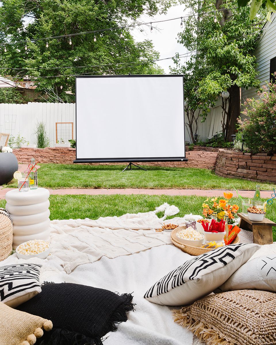 Casual modern lounge setup with outdoor movie screen and layered neutral textiles