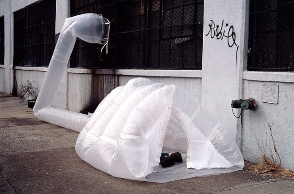 Minimalist white inflatable shelter with curved design and ventilation tube in urban setting
