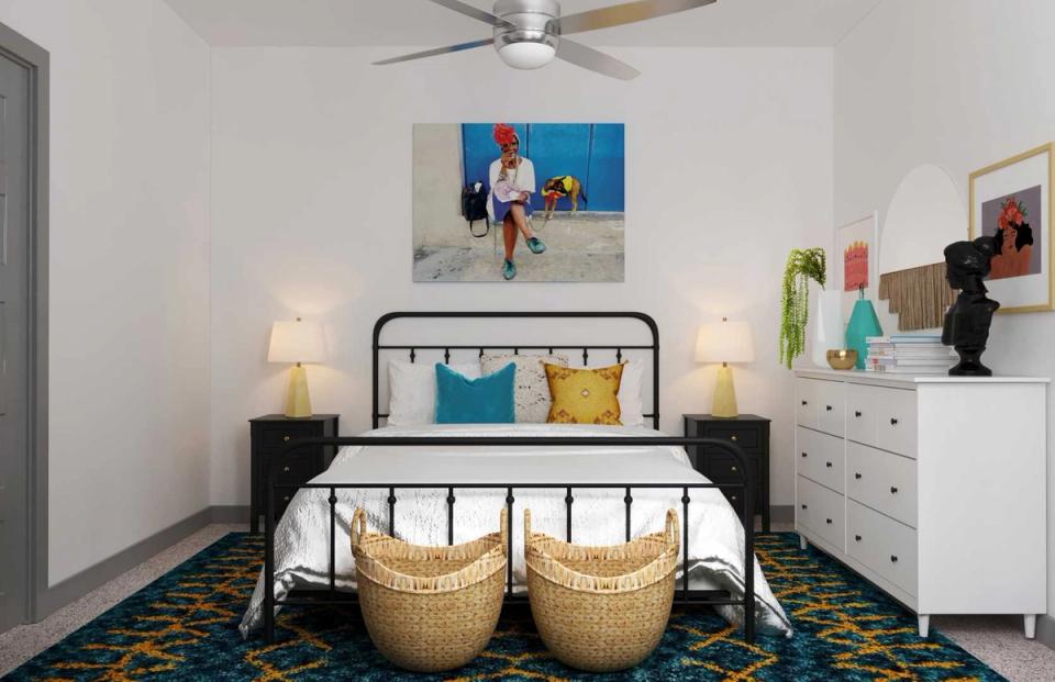 Modern bedroom with black metal bed frame, curved woven ottomans, teal and navy accents, and geometric patterned rug.
