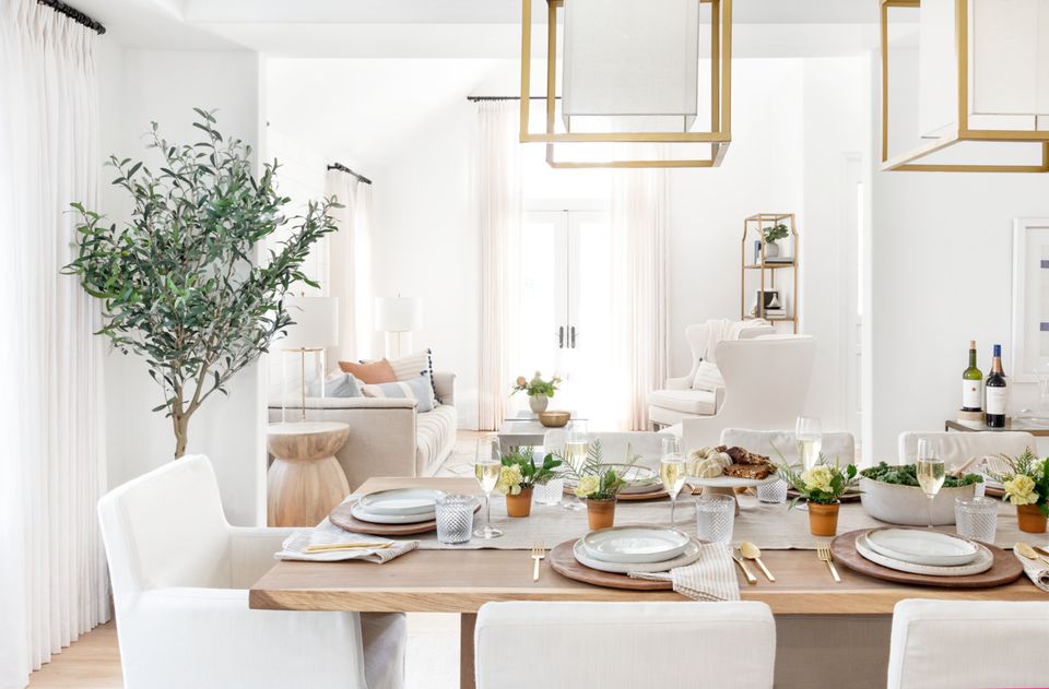 Scandinavian dining room with natural wood table, white chairs, potted tree, and warm minimalist aesthetic with brass fixtures