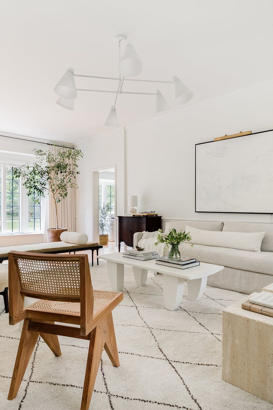 Minimalist organic modern space with cream sofa, natural wood chair, potted greenery, and warm earth-tone accents