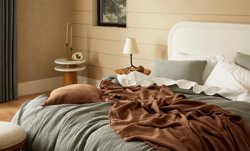 Warm, earthy bedroom with caramel and sage tones, layered textures, and minimalist nightstand styling