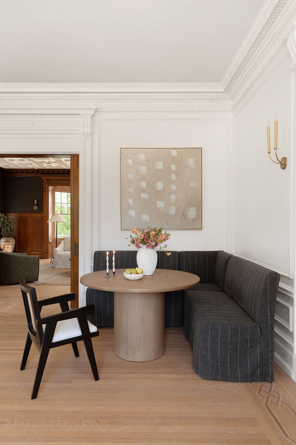 Transitional dining nook with charcoal banquette, round wood table, and minimalist neutral palette