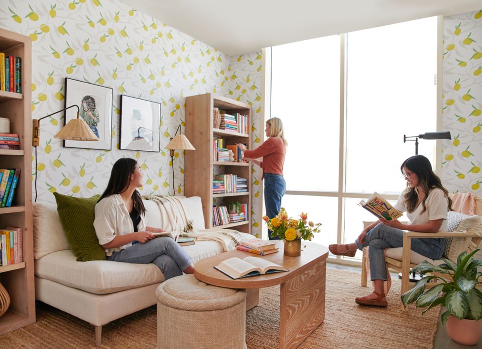 Bright multi-functional reading space with lemon wallpaper, cream seating, natural wood furnishings, and shared gathering area