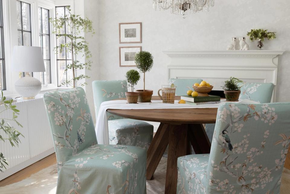 Classic dining room with sage floral chairs, round wood table, and soft blue palette