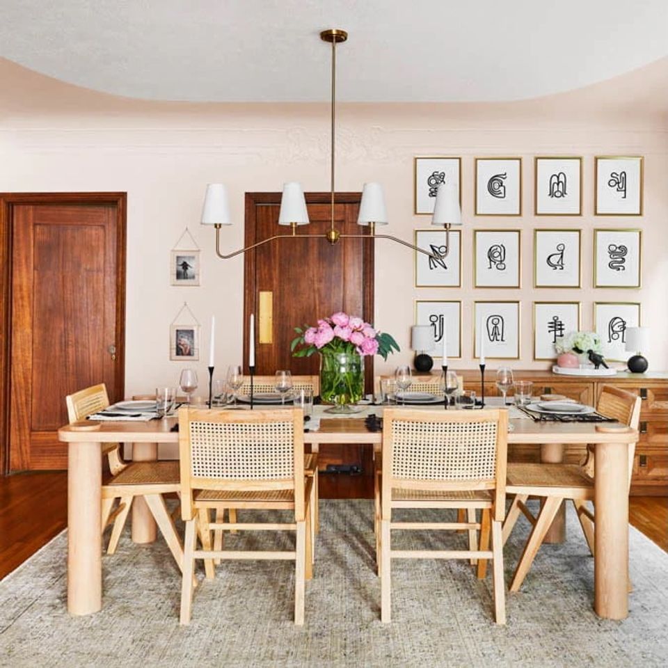 Refined dining room with pale pink ceiling, warm wood tones, natural rattan chairs, and eclectic gallery wall in sophisticated traditional style.