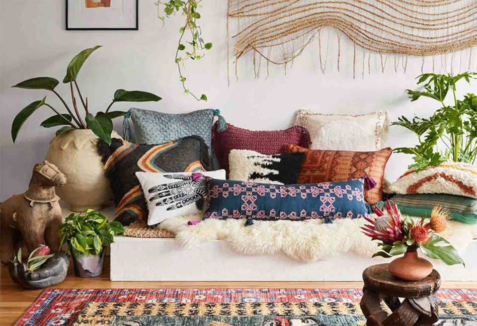 Bohemian bedroom with layered textiles, macramé wall hanging, rich jewel tones, and lush greenery creating a warm, eclectic aesthetic.