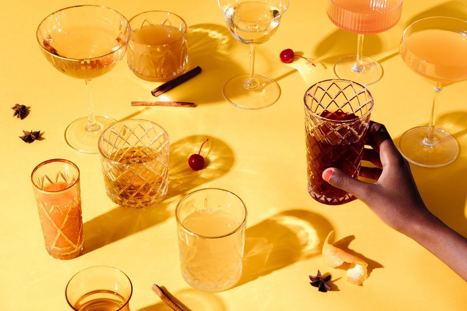 Warm golden flatlay with cocktail glasses, amber drinks, and festive party styling on yellow background