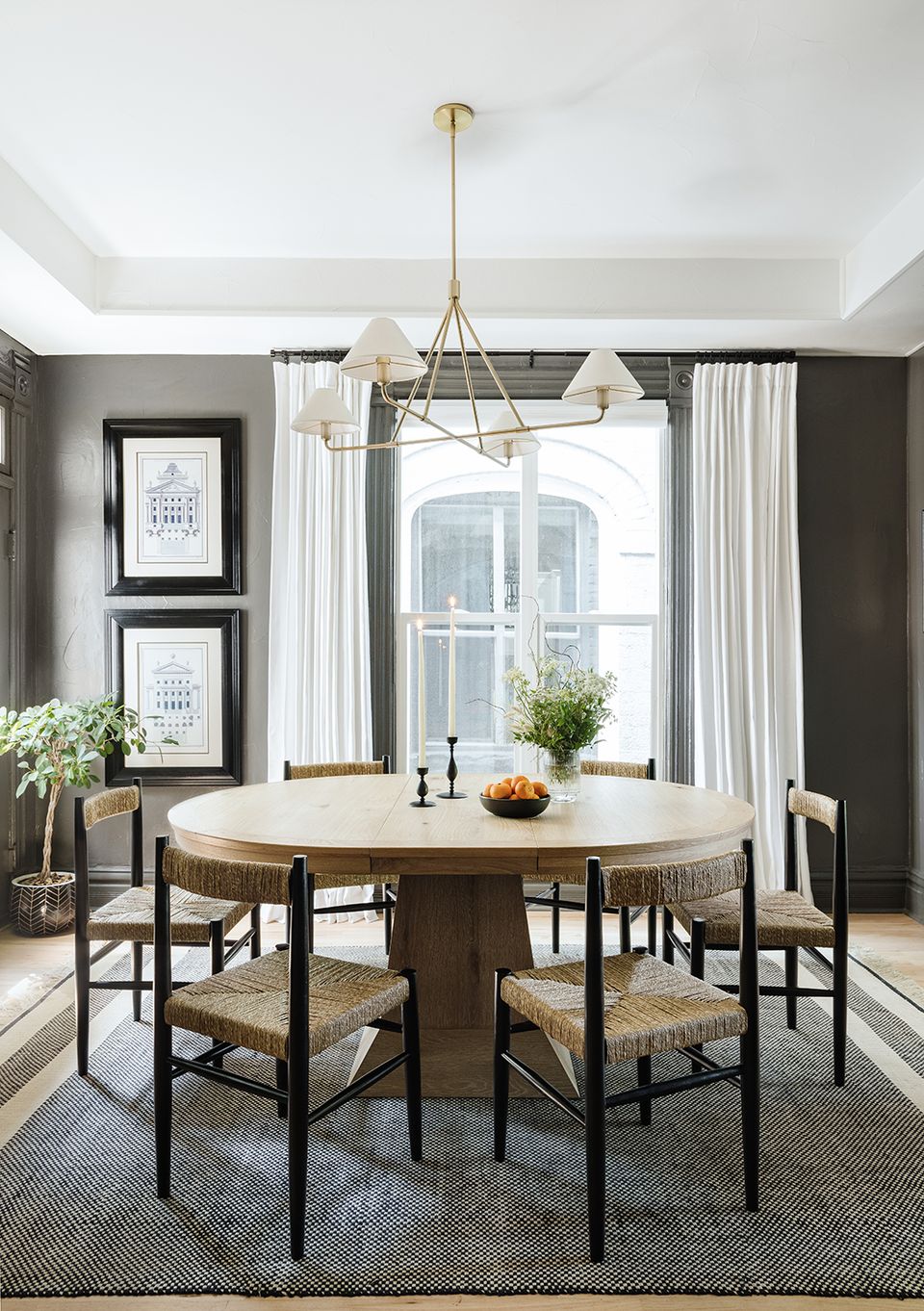 Contemporary dining space with charcoal walls, natural wood table, and refined brass pendant lighting