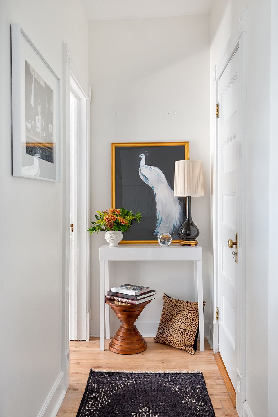 Bright entryway with clean white walls, warm wood tones, and curated art displaying elegant, intentional styling
