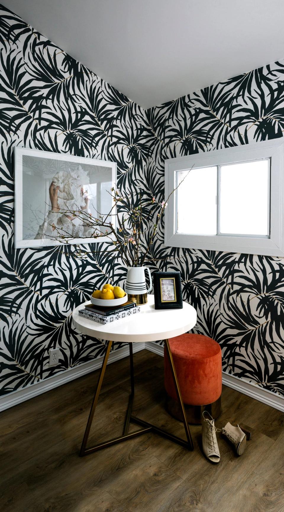 Bold black and white botanical peel-and-stick wallpaper creates dramatic maximalist accent wall in modern workspace with mid-century furniture.