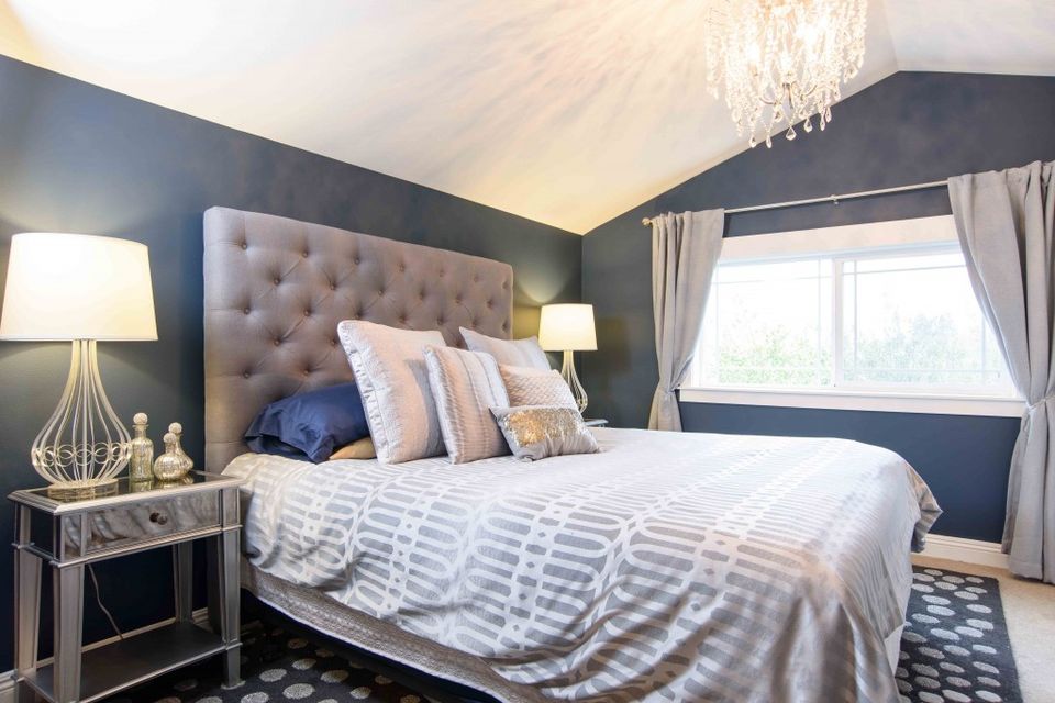 Contemporary bedroom with navy accent wall, tufted headboard, and elegant crystal chandelier lighting