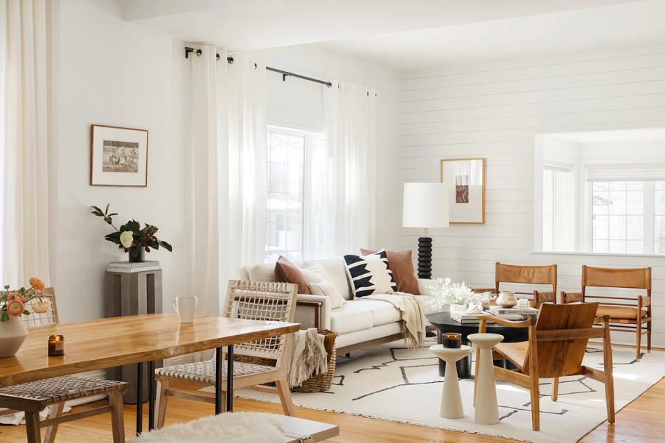 Airy farmhouse living room with natural wood dining table, cream sectional, and warm wood tones in relaxed, inviting style.