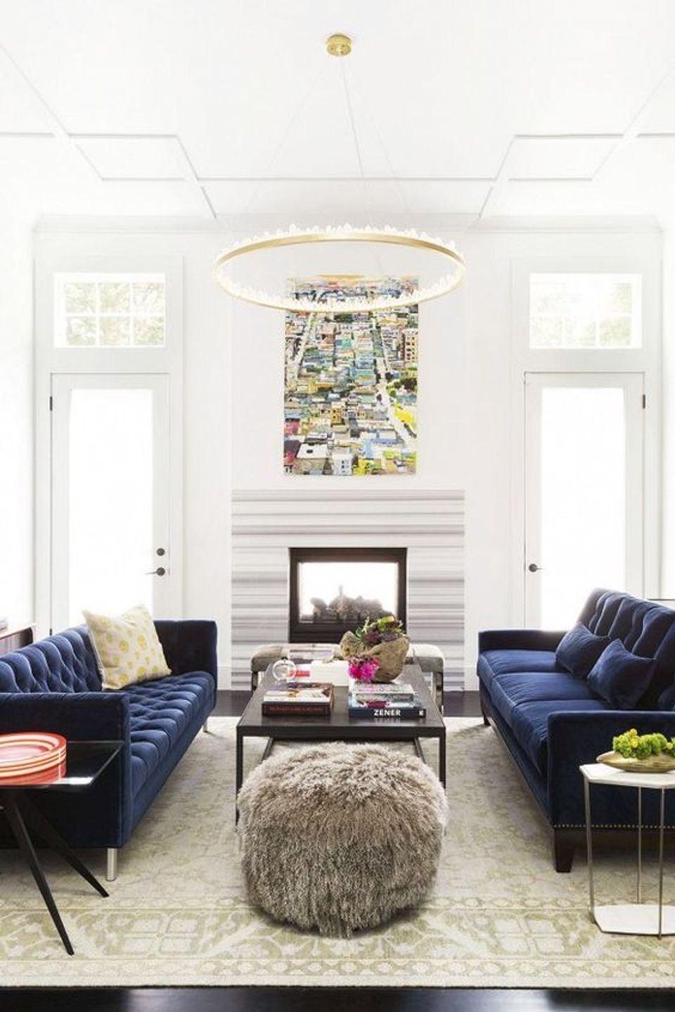 Sophisticated living room with navy velvet sofas, brass chandelier, and contemporary fireplace