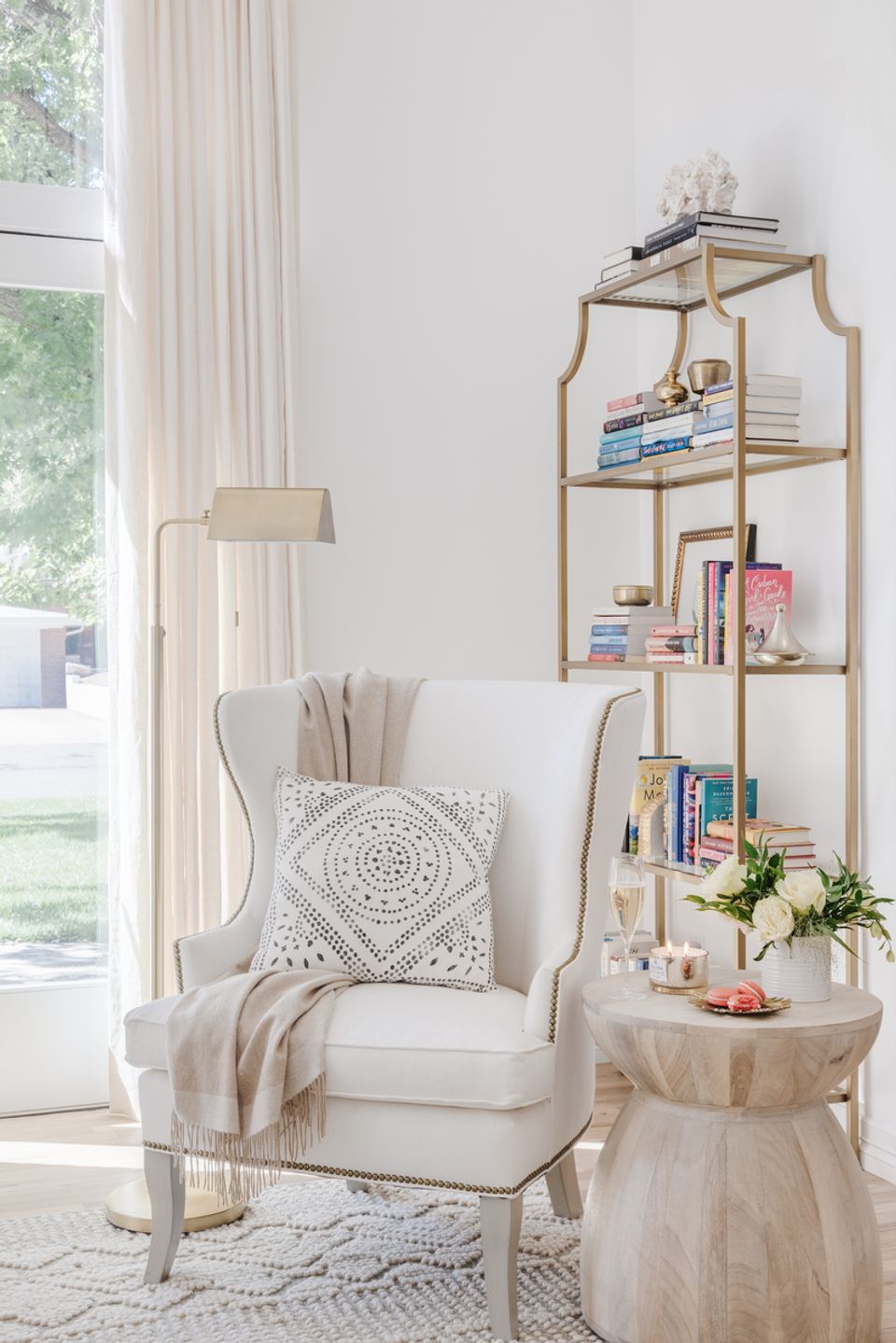 Serene Scandinavian reading nook with cream wingback chair, natural wood shelving, and soft ambient lighting