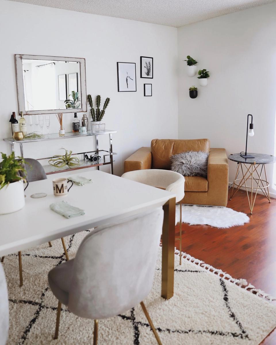 Eclectic workspace mixing cognac leather chair, white desk, vintage mirror, and warm wood tones