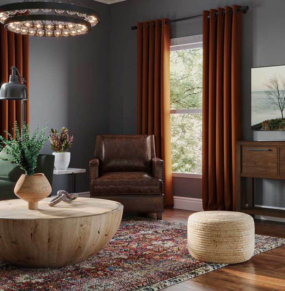 Warm transitional living room with charcoal walls, cognac leather chair, rust drapes, and wooden round table