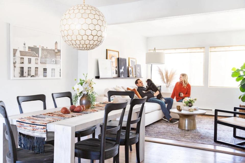 Bright modern dining space with black chairs, marble table, crystal pendant light, and neutral palette creating an airy, sophisticated atmosphere.
