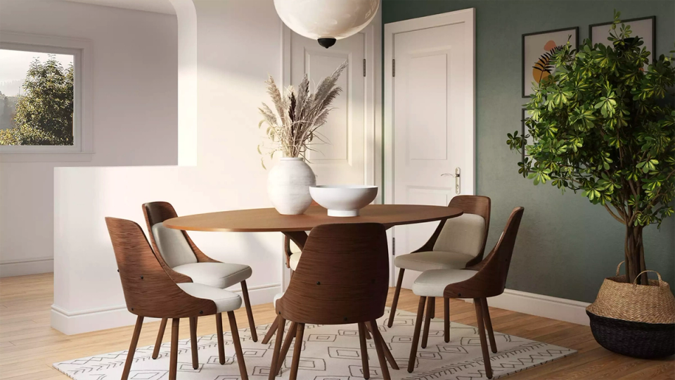 Modern organic dining space with warm wood round table, terracotta chairs, and sage green accent wall