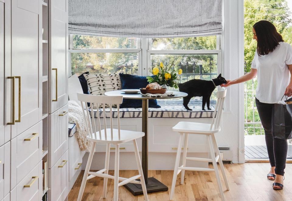 Bright, minimalist home office with scandinavian aesthetic, natural light from bay window, black and white palette, woman with cat in relaxed workspace