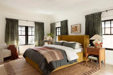 Eclectic modern bedroom with mustard wood bed, olive curtains, striped bedding, and warm wood and natural fiber accents