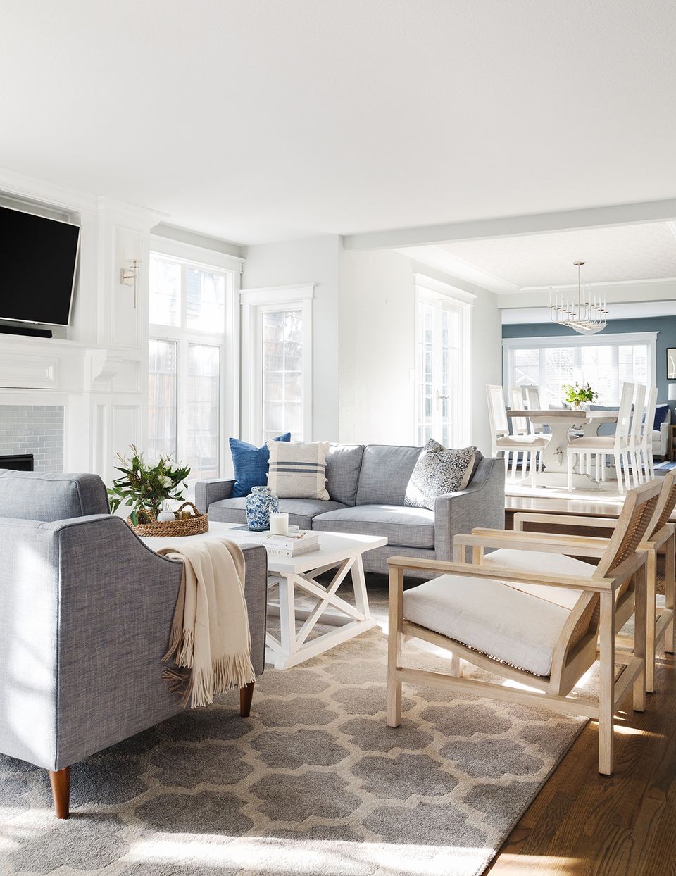 Bright, airy coastal living room with soft gray seating, crisp white trim, natural wood tones, and serene neutral palette