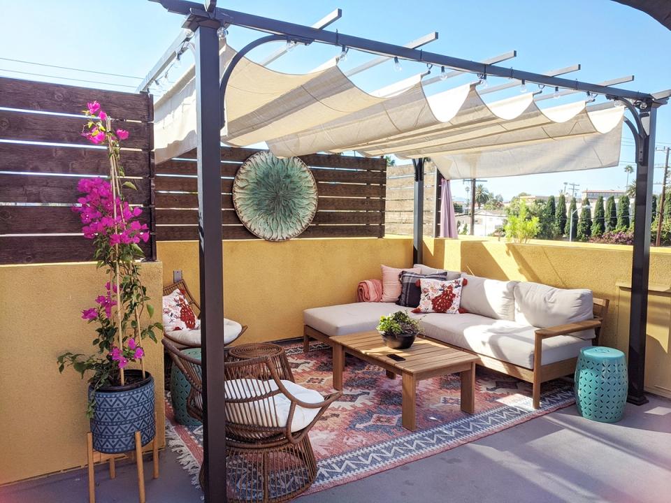 Eclectic boho-chic rooftop with mustard walls, patterned rugs, white seating, and bohemian layered décor.