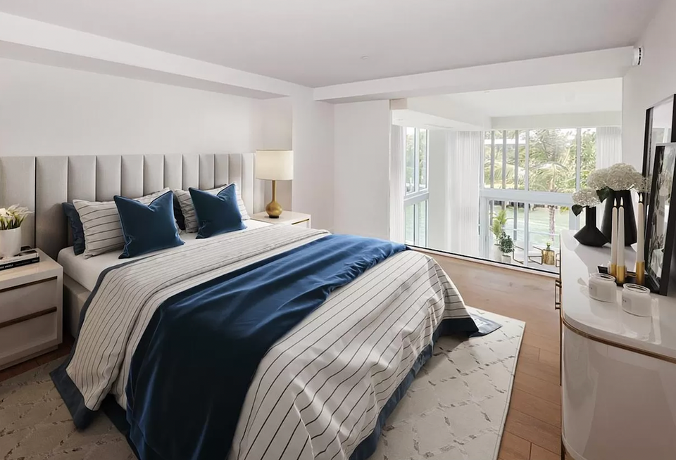 Serene bedroom with upholstered headboard, navy blue accents, striped bedding, and bright natural light.