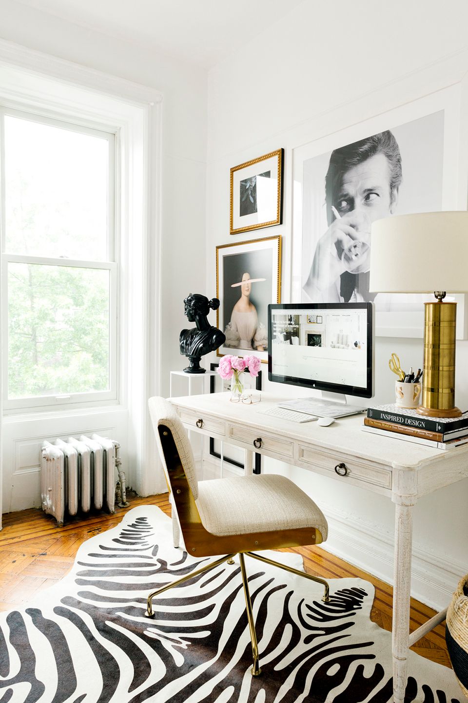 Chic contemporary desk with black-and-white gallery wall, zebra print rug, and metallic accents