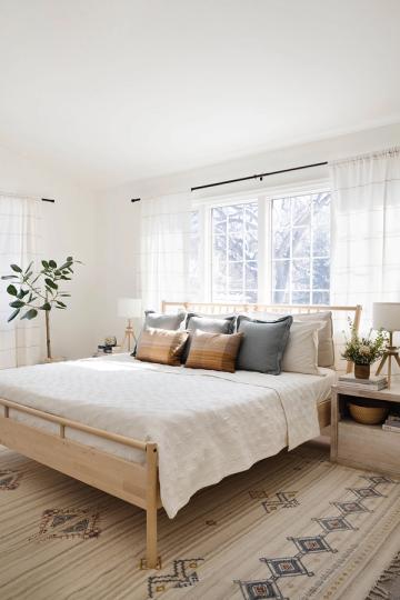 Tranquil organic modern bedroom with light wood bed frame, layered neutral bedding, and geometric area rug